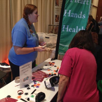 Collegiate volunteer assists with virtual goggles.